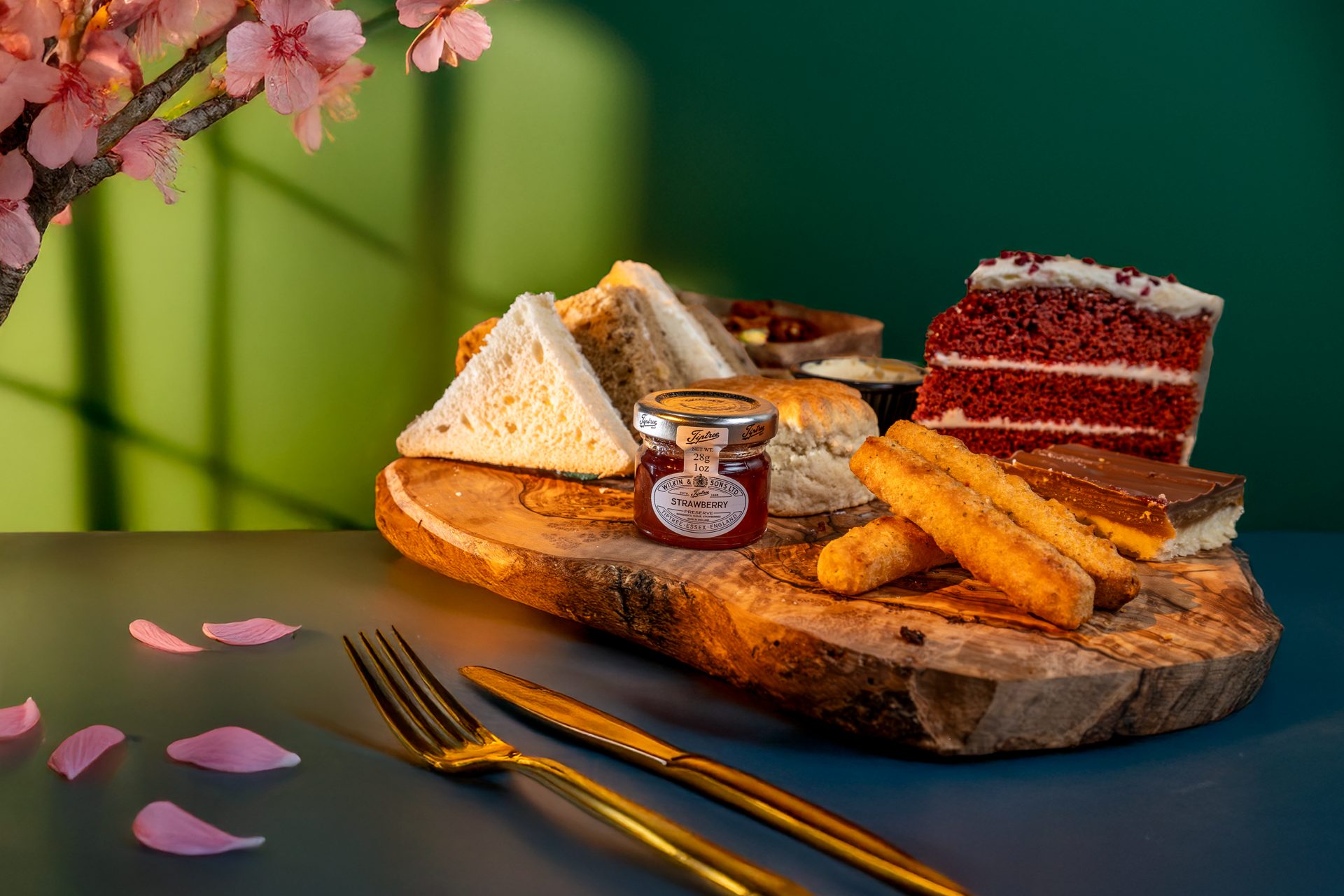 Three-tier afternoon tea stand with pastries, scones and a coupe of champagne
